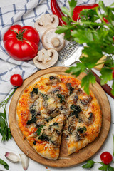Homemade pizza with tomatoes, spinach and mushrooms.