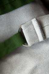 green strap with metal fittings on a light textile background, close-up