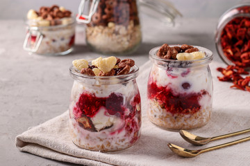 Oatmeal, granola with berries, strawberry chips, cottage cheese and natural yogurt, a delicious and healthy breakfast, located in glass jars on a gray background, Horizontal format