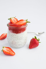Pudding with chia and  strawberry  in the  glass jar on the white background. Closeup. Location vertical.