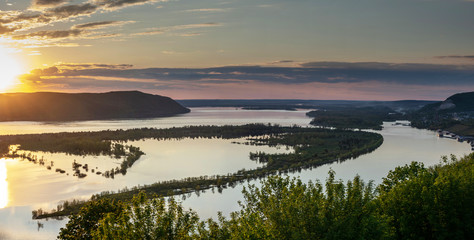 Fototapeta premium Dramatic sky during sunset over Volga river in front of Zhighuli hills at embankment near Samara city, Russia