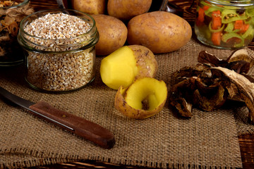peeled potato and barley groats, dried plums next to dried mushrooms and dried spices