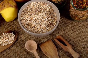 barley on wooden spoons, dried plums next to one peeled potato and dried mushrooms next to dried spices