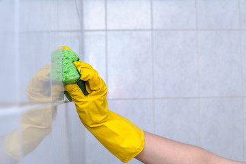 woman washes a sponge in the bathroom white tiles on the wall close-up. House cleaning.