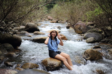 Woman sitting on a rock at Trok Nong Waterfall in Chanthaburi, Thailand