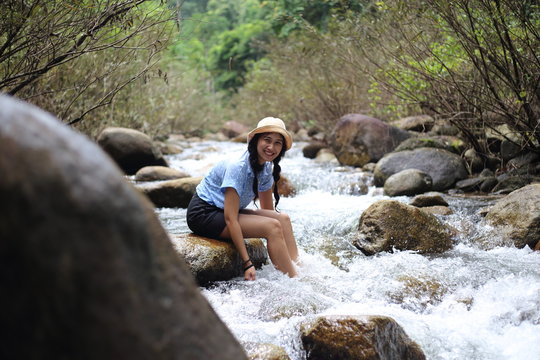 Woman sitting on a rock at Trok Nong Waterfall in Chanthaburi, Thailand