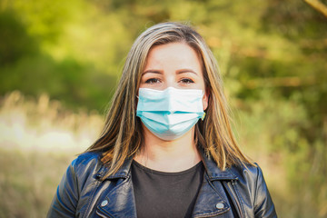 Young blonde hair woman with her face mask on the walking in the park. She is looking forward to the end of corona virus - COVID 19 and quarantine.