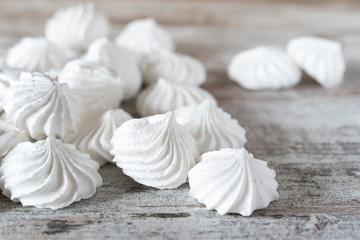 Obraz premium Small white meringue cookies on wooden rustic table