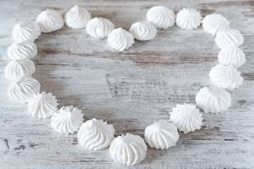 Small white meringues laid out in the shape of a heart on a wooden rustic table