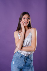 A young beautiful girl shows emotions and smiles in the Studio on a purple background. Girls for advertising