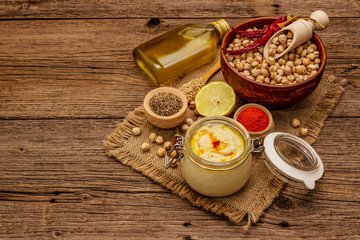 Hummus on old wooden boards background. Dry chickpea, olive oil, lemon, cumin and chili pepper