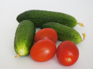 green cucumbers and red tomatoes close up on a white background