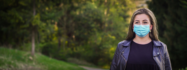 Naklejka premium Banner young blonde hair woman with her face mask on the walking in the park. She is looking forward to the end of corona virus - COVID 19 and quarantine.