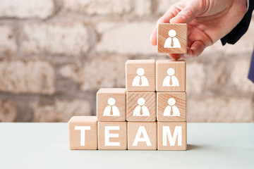 Businessman hand arranging wood block stacking with business team concept.