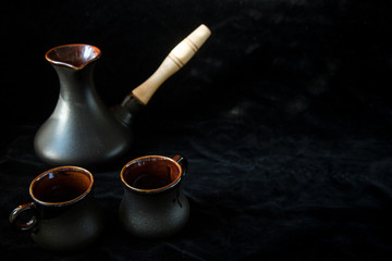 Obraz na płótnie Canvas Two black cups for coffee and black turk isolated on black background, place for text. Sweet home