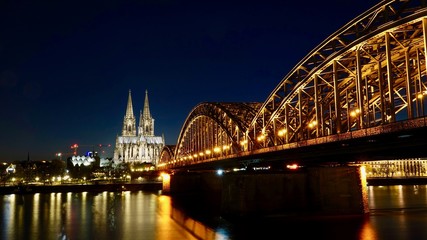 Fototapeta premium Kölner Dom und Hohenzollernbrücke im Sonnenuntergang am Abend