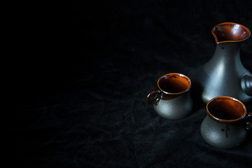 Obraz na płótnie Canvas Two black cups for coffee and black turk isolated on black background, place for text. Sweet home