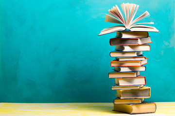Composition with vintage old hardback books, diary, fanned pages on wooden deck table and abstract background. Books stacking. Back to school. Copy Space. Education background.
