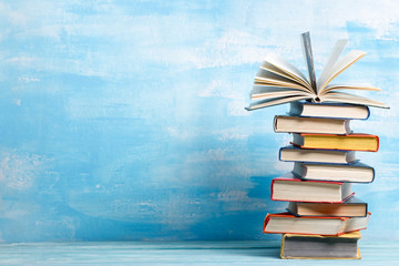 Fototapeta premium Composition with vintage old hardback books, diary, fanned pages on wooden deck table and abstract background. Books stacking. Back to school. Copy Space. Education background.