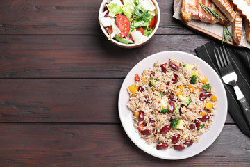 Delicious rice with beans served on wooden table, flat lay. Space for text