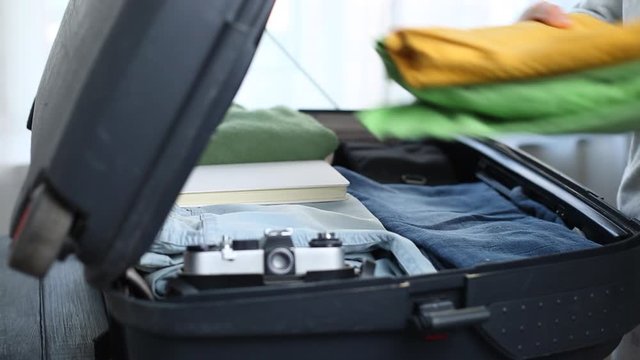 A woman puts things into a suitcase about to travel. Vacation concept