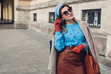 Fototapeta premium Spring vintage retro fashion female accessories and clothes. Woman wearing sweater beret leather skirt purse on street.
