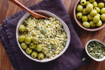 Bulgur with green olives and pepitas, healthy nutrition easy recipe from long-stored food.