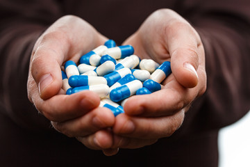 Kids hands holds handful of pills.