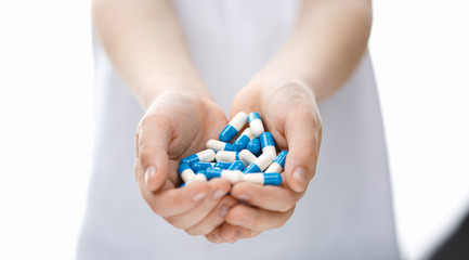 Kids hands holds handful of pills.
