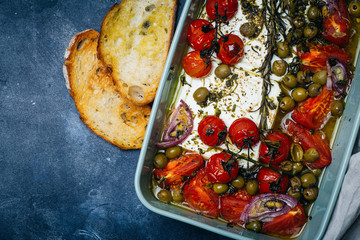 Fototapeta na wymiar Baked vegetables with feta cheese, olives, onions, Provencal herbs, spices, olive oil and tomatoes. Home cooking concept.