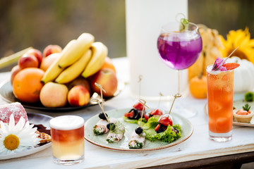summer catering buffet with canap snacks with eggplant, olives, herbs, tomatoes and meat. With cocktails and fruits