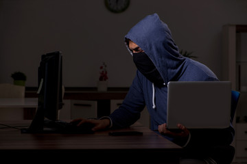 Male hacker hacking security firewall late in office