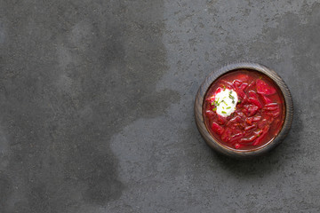Obraz na płótnie Canvas Beetroot soup with greens and sour cream in a wooden bowl on a dark gray background top view