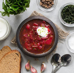 Beetroot soup with greens in a wooden bowl on a light background top view