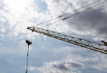 crane boom at a construction site. Against the background of blue sky and bright sun.
