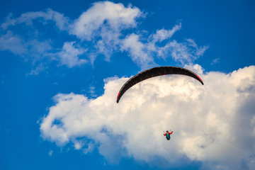 Flying paraglider on a background of blue sky with clouds.