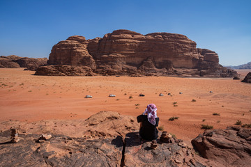 Fototapeta na wymiar Turista osserva il panorama nel deserto Wadi Rum, Giordania
