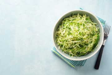 Fresh cabbage and cucumber salad with dill in bowl on concrete background. Coleslaw.