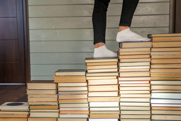 Woman legs on white socks going up to books stairs