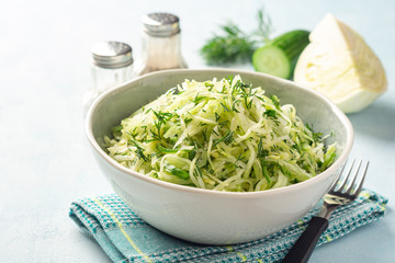 Fresh cabbage and cucumber salad with dill in bowl on concrete background. Coleslaw.
