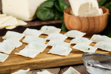 uncooked raw Russian national dish vareniki dumplings with cheese, butter and spinach