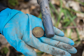 Found ancient old precious coin in the digger's .archaeologist  hand with pinpointer metal detector. A valuable .historical find in the forest