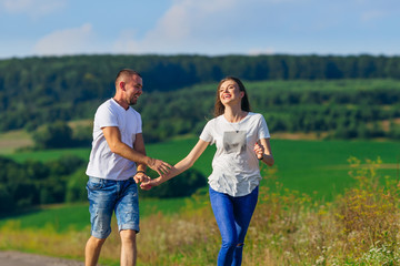 couple in casual clothes holding hands and running against fores