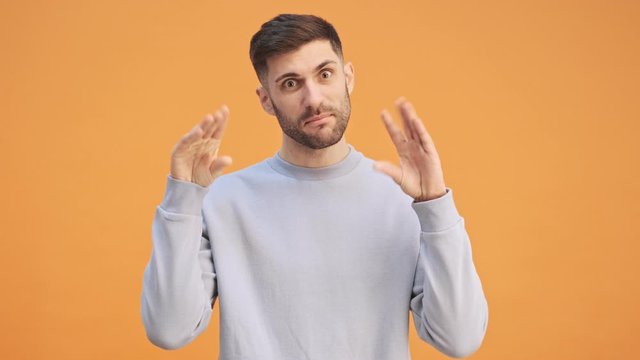 Young sarcastic man isolated over yellow wall background make blah blah gesture