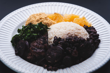 Feijoada com ingredientes ao fundo