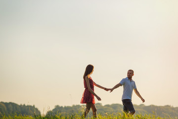 Fototapeta premium Happy couple is walking together in green field. summer. meadow,