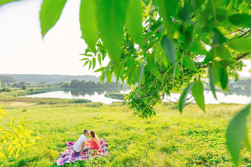 girl and guy kissing on a picnic. beautiful meadow by the lake a