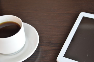 Obraz na płótnie Canvas empty tablet and a cup of coffee on the black desk