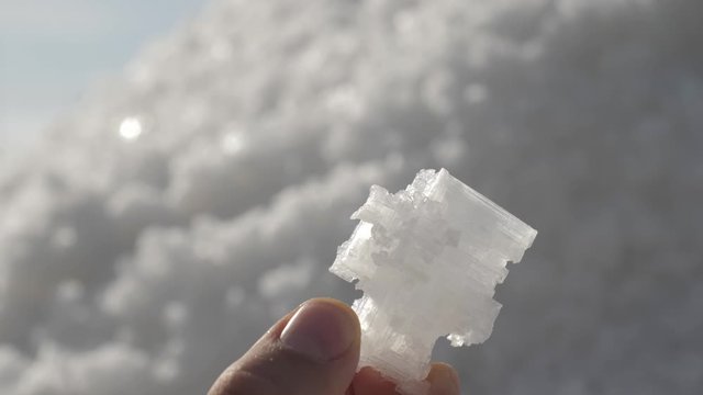 raw salt crystals in hands. Male hand holding natural salt crystals on the background of a salt lake. White natural salt. natural resources concept,