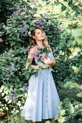 Obraz na płótnie Canvas A beautiful happy young woman enjoys the smell in a blooming spring Lilac garden. Happy beautiful woman enjoying nature. A trendy modern look .